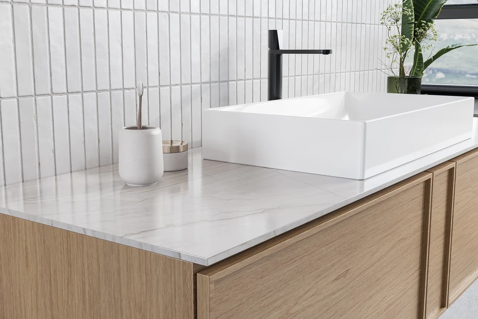 Un installateur professionnel en polo noir et ceinture à outils examine une paroi de douche vitrée dans une salle de bain moderne aux murs blancs