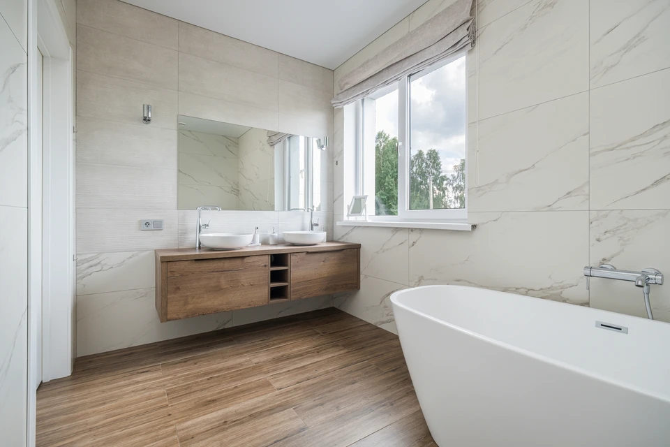 Plombier professionnel en uniforme noir avec ceinture à outils installant ou réparant une robinetterie noire moderne au-dessus d'un lavabo vasque blanc